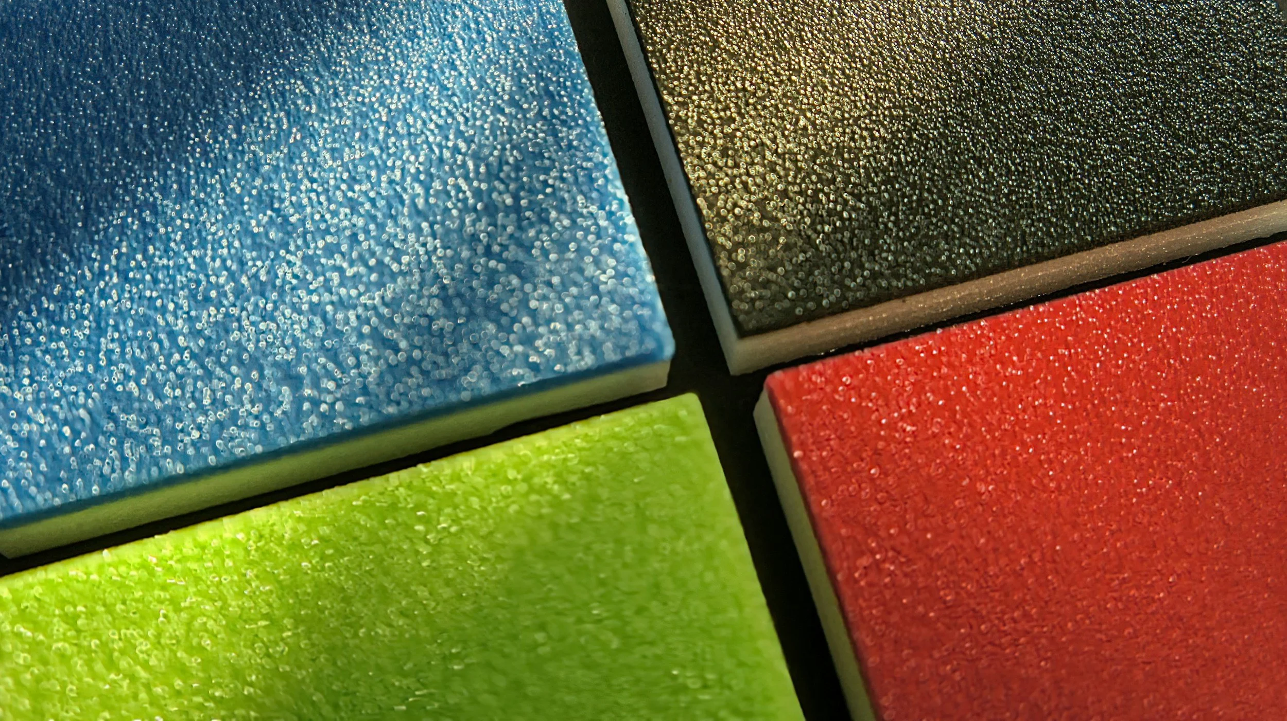 Close-up of colorful foam sponges in blue, yellow, red, and green with textured surfaces.