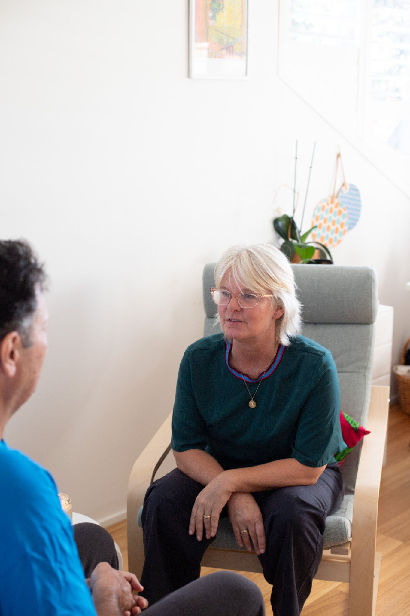 Tina is speaking to a client while sitting in an arm chair.