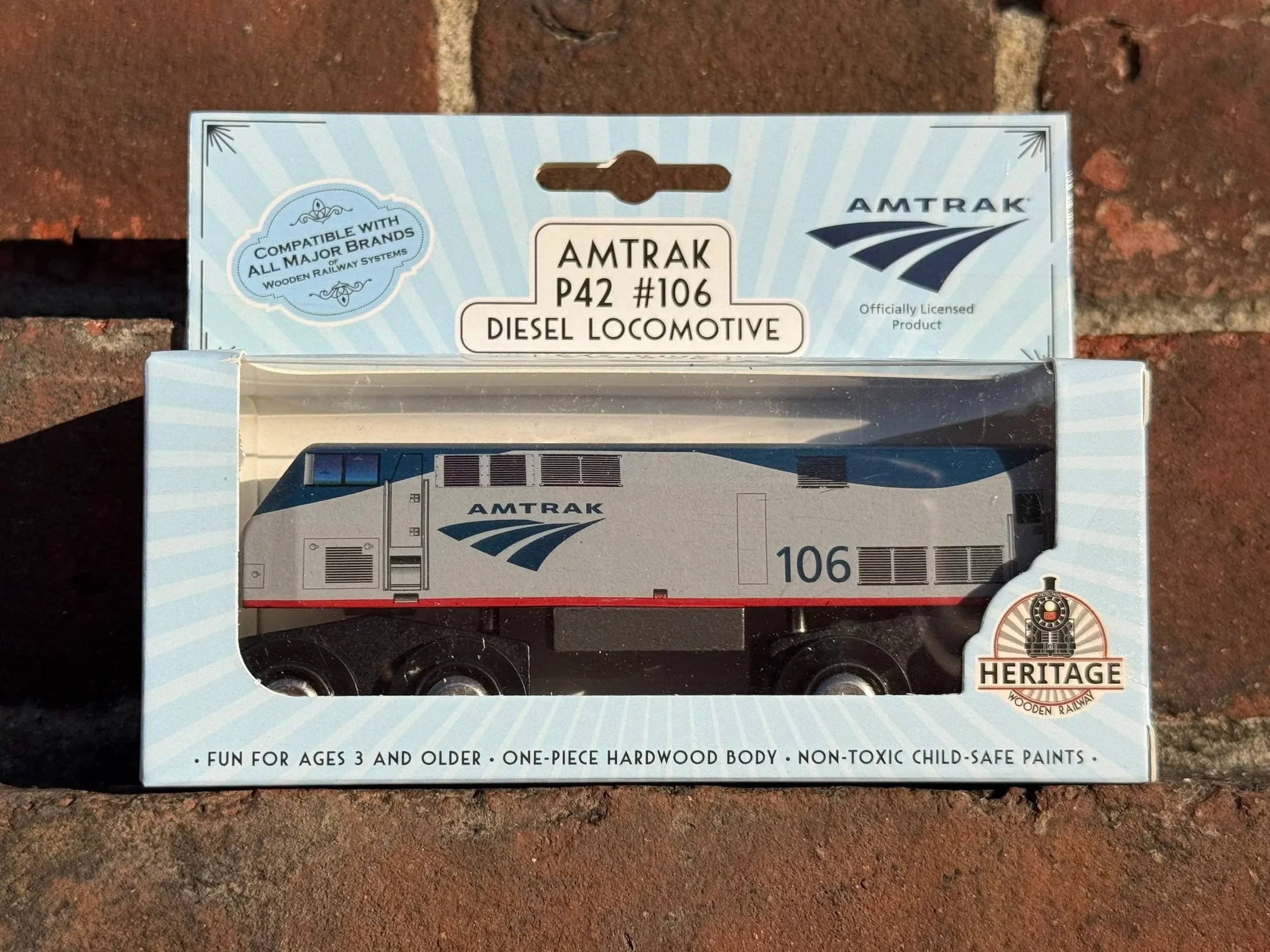 A wooden toy train in packaging, modeled after an Amtrak diesel locomotive, with the branding 'Heritage' and model P42 #106.