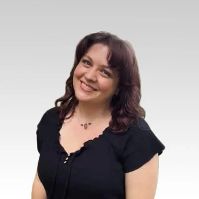 A woman with shoulder-length brown hair, smiling, wearing a black top, against a plain light gray background.