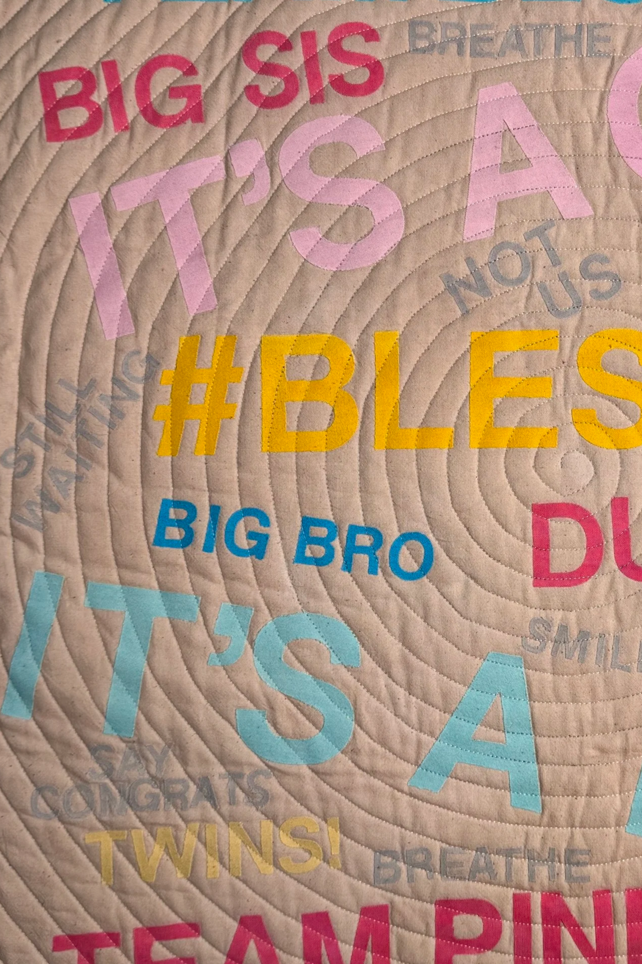 Textual quilt with baby announcement language and a spiral quilting.