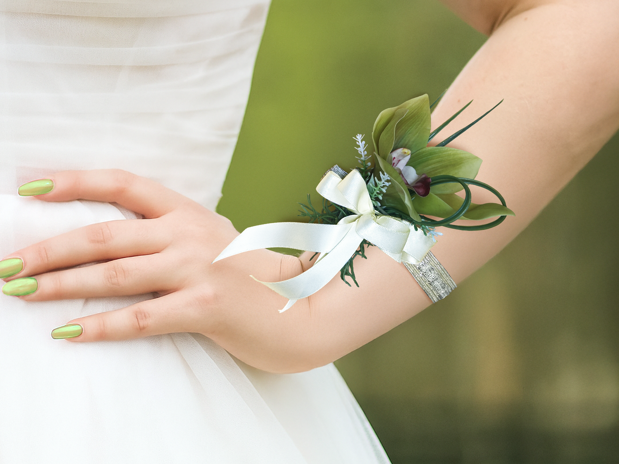 Green and white corsage on wrist outside.png