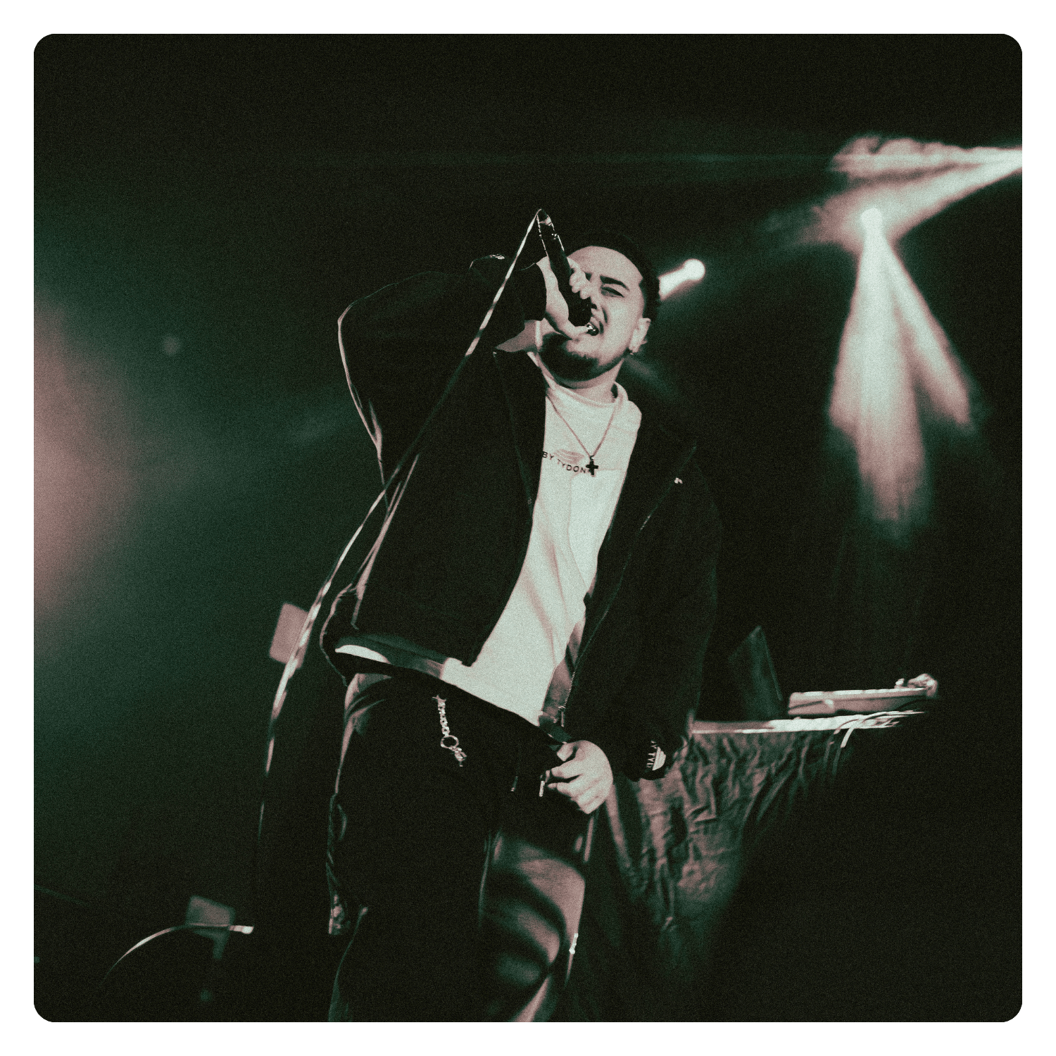 A male performer singing into a microphone on stage with lighting.