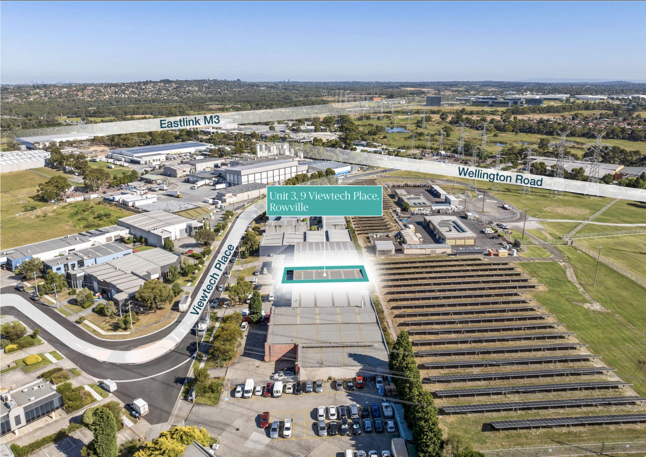 Aerial view of industrial and commercial area with labeled streets Eastlink M3 and Wellington Road, featuring buildings, parking lots, solar panel installations, and surrounding greenery in Rowville.