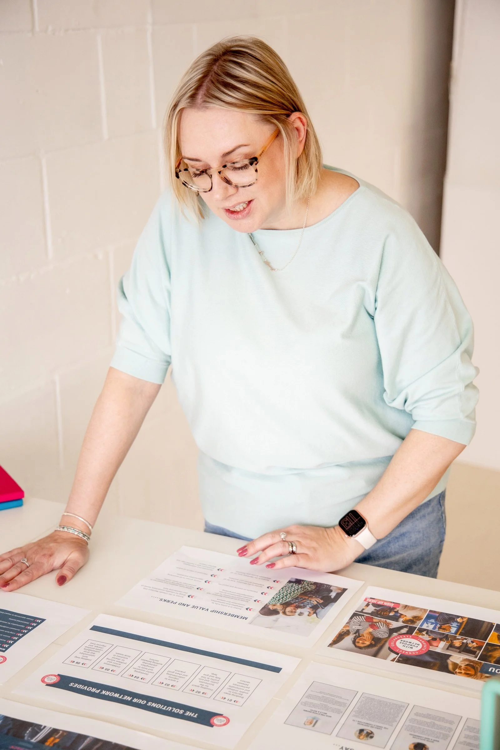 Sadie Finch, founder of More Than Admin, looking at documents and promotional materials on a table.