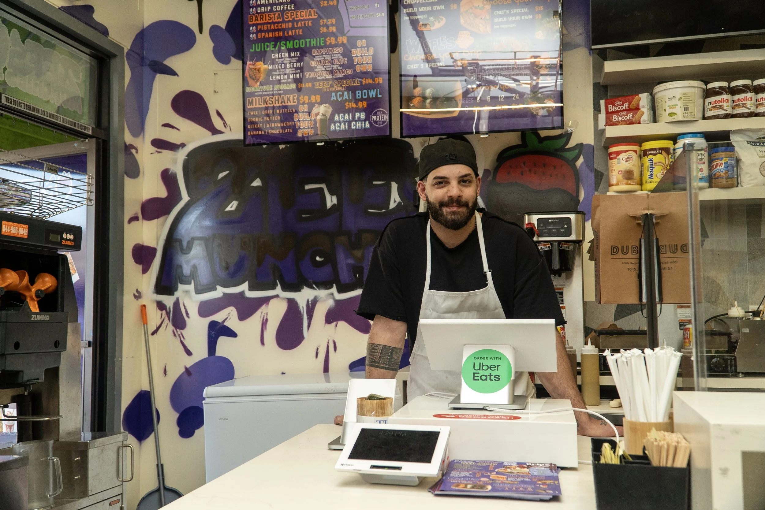  Abood Sluimen, manager of the new San Francisco location of Zee’s Munchies, poses for a photo at its new location in Abraham’s Farmers Market on Geary Boulevard, on March 21, 2026. (Neal Wong / Richmond Review) 