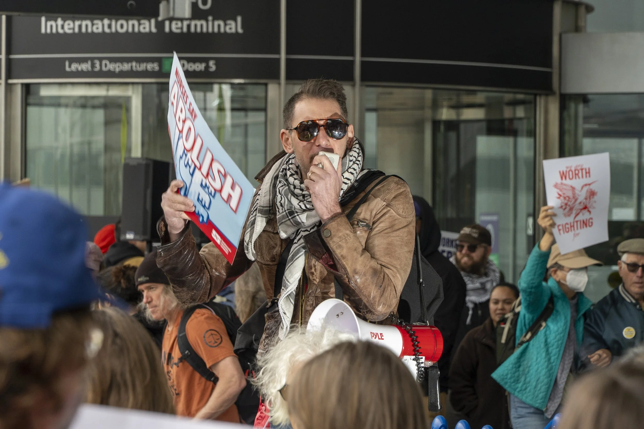  A chant leader speaks into a megaphone at the San Francisco International Airport May Day rally, where workers and community members protested against billionaire greed and the Trump administration’s cuts to federal programs. (Neal Wong / San Franci