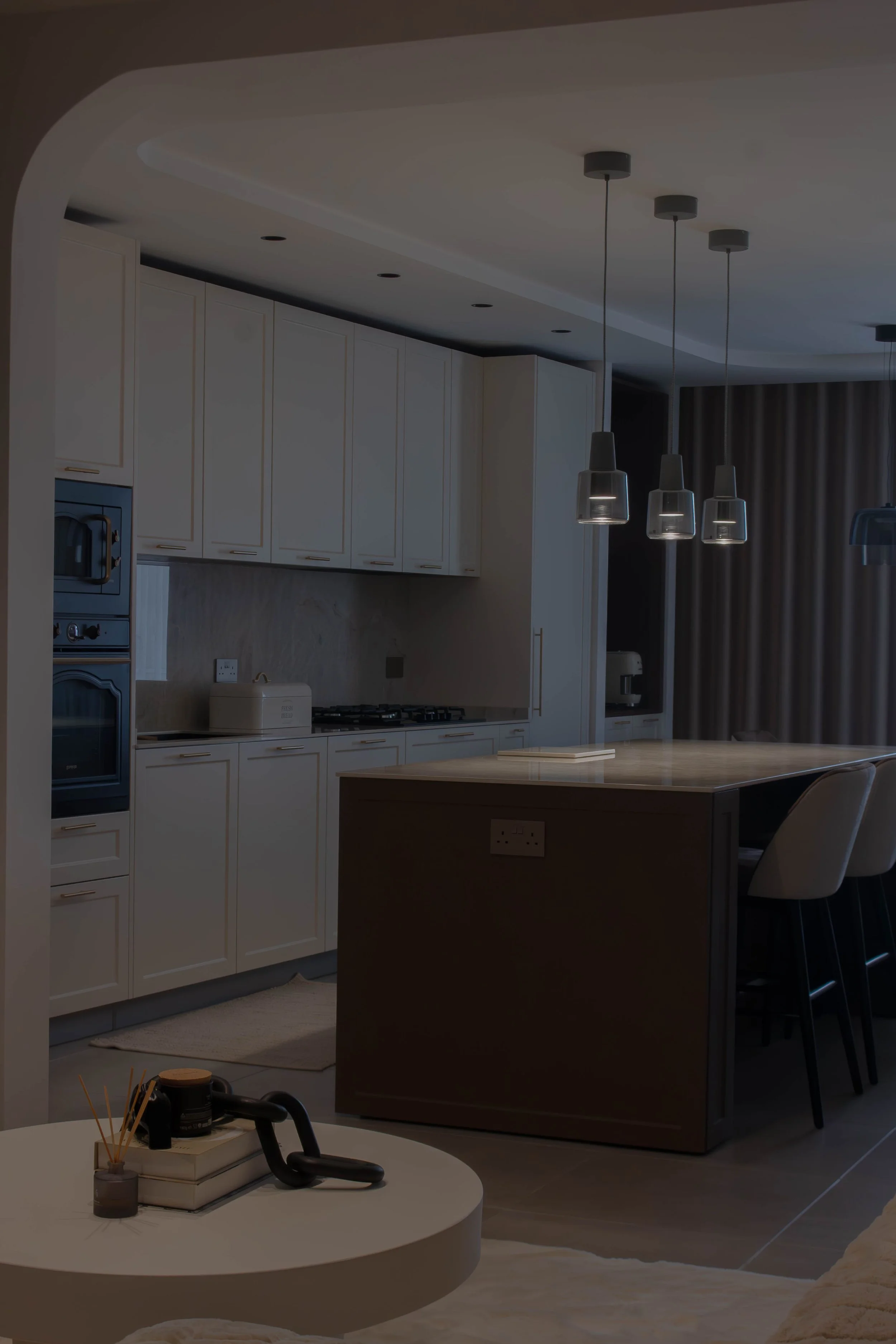Modern kitchen with white cabinets, pendant lights, and a marble kitchen island in the background.