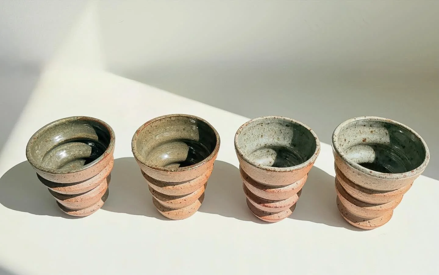 Reduction-fired Ziggurat Cups. Thrown on the wheel and left unglazed on the exterior to reveal the raw, speckled clay. The interiors are glazed &mdash; some with celadon (left) and others with transparent glaze (right).

These are coming with me @han