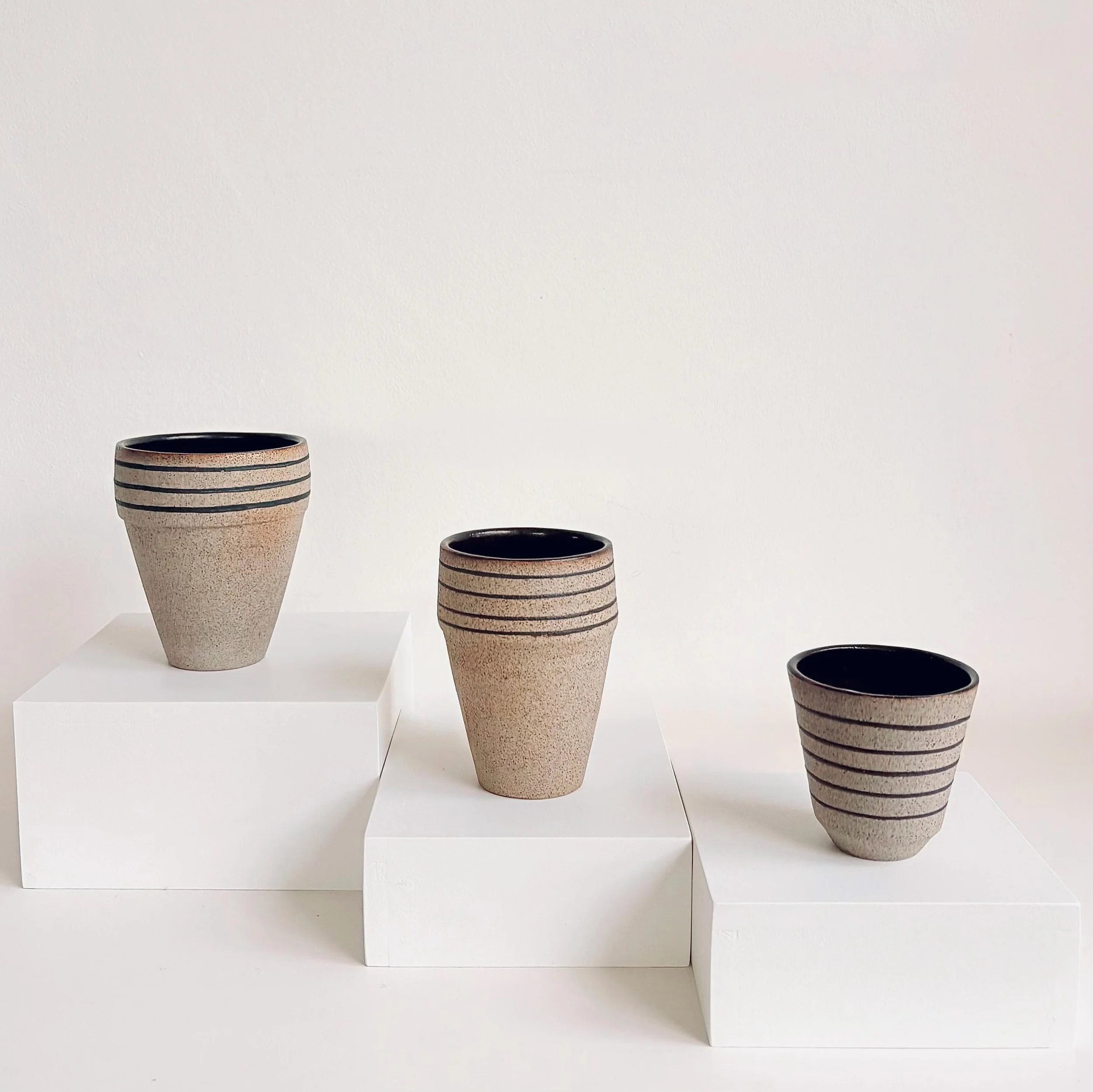 Graduated ceramic cups, wheel-thrown in grey speckled clay with black slip inlay lines and a matt black glazed interior.

#contemporaryceramics#wheelthrown#ceramiccups#slipinlay#londonceramics