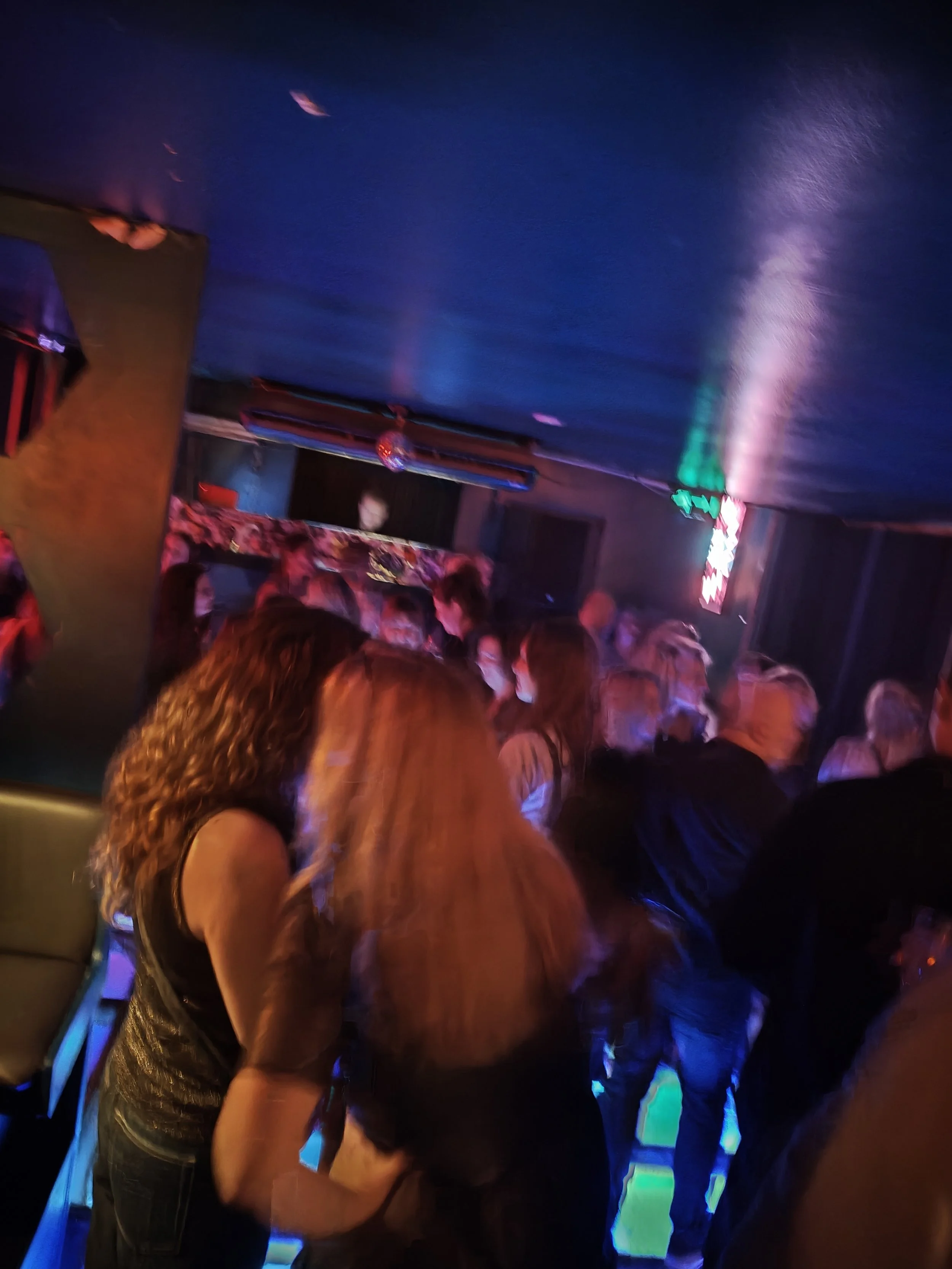 Mennesker, der danser og hygger sg i en dæmpet natklub med farverige LED-lys.