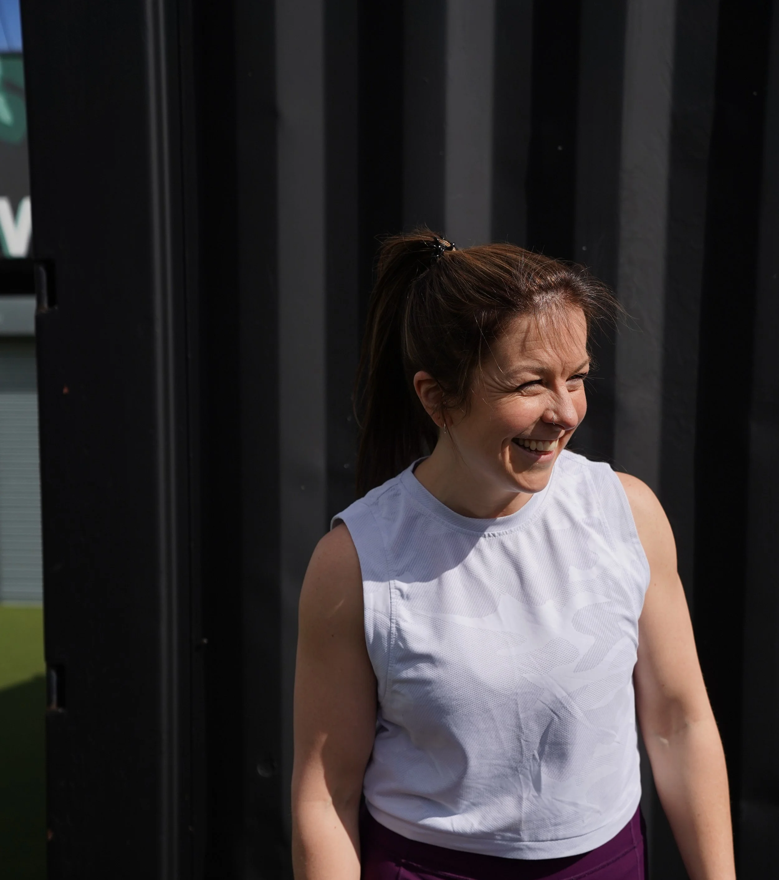 Meg, the coach, stood smiling in the sunshine promoting her business.