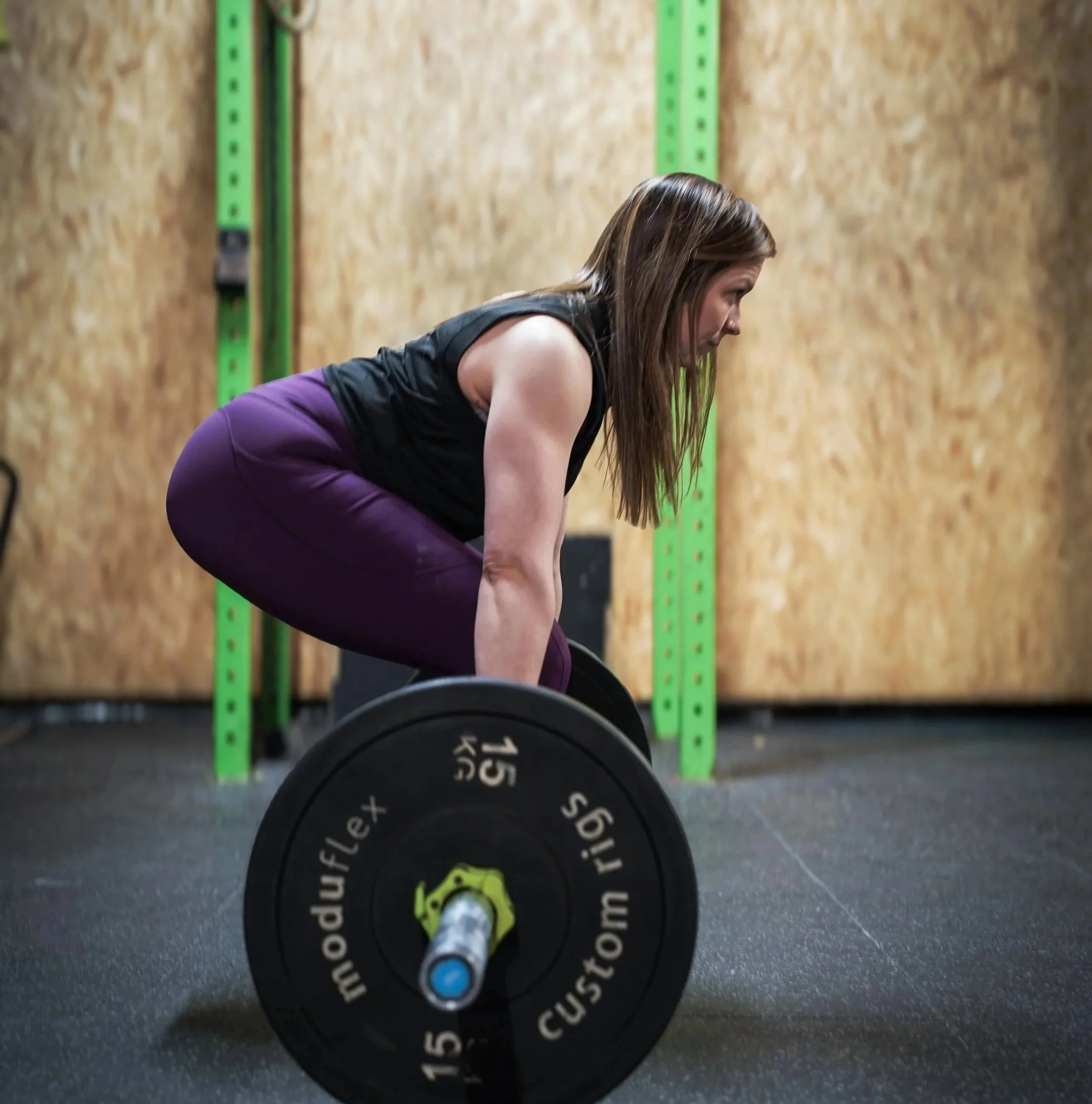 A woman is performing a deadlift with a barbell in a gym.