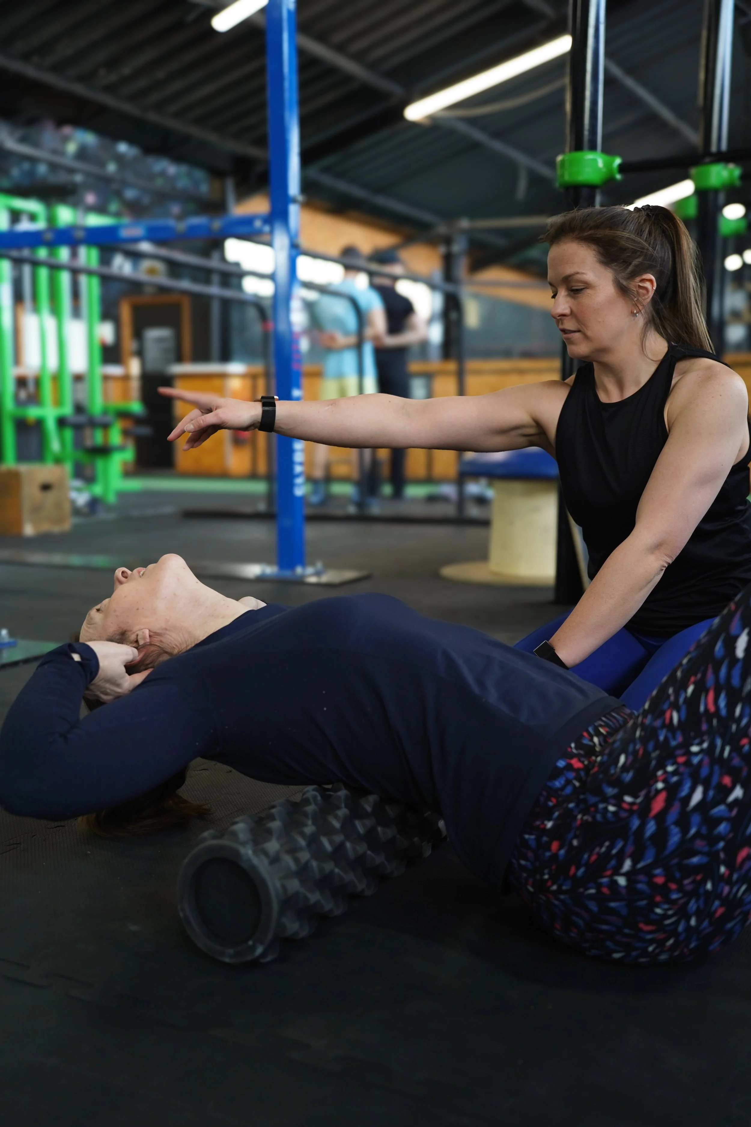A female client is being walked through a mobility exercise during a show me how session. The coach is providing cues to enhance this exercise for her client.