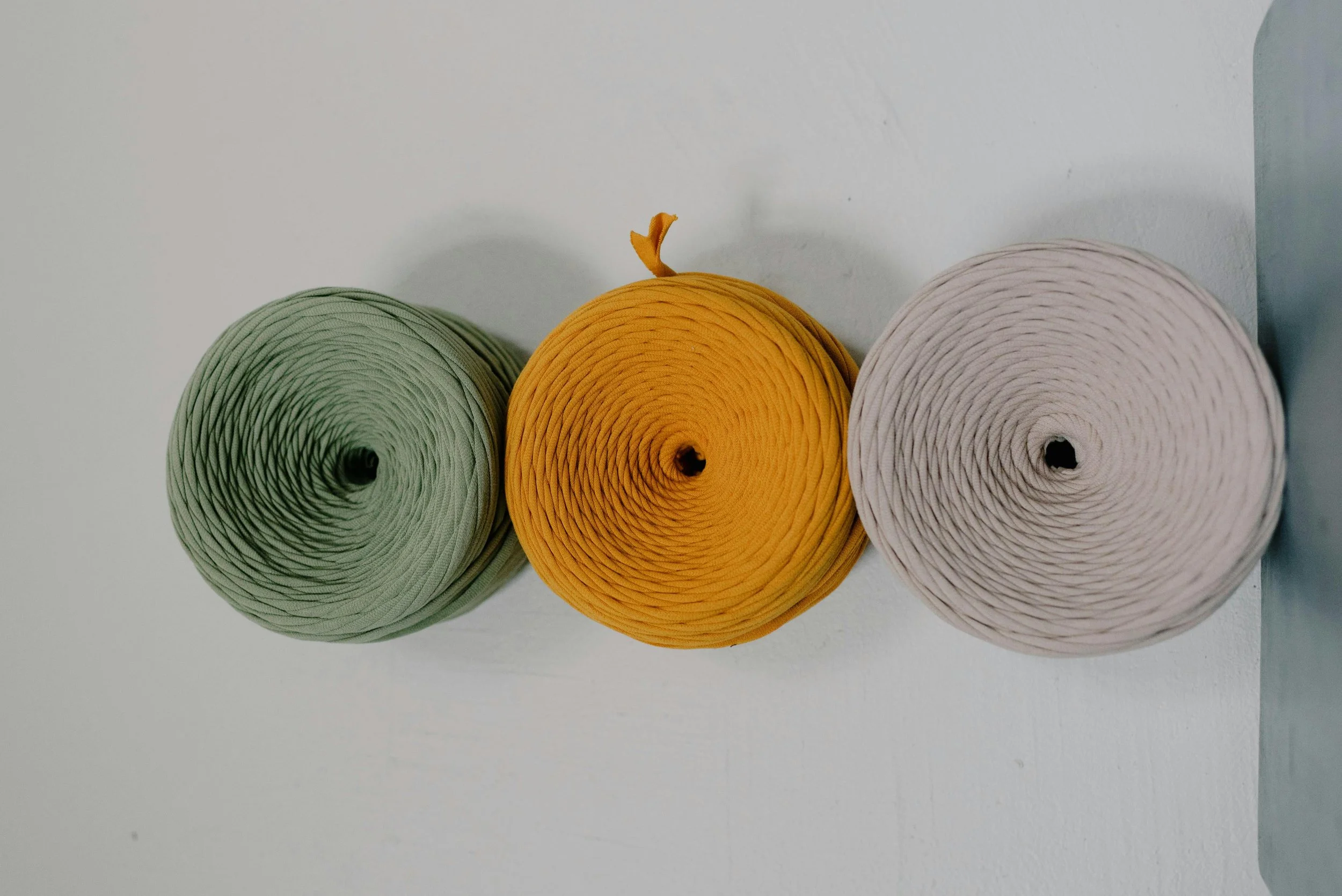 Three rolls of paper in green, yellow, and white colors aligned on a white surface.