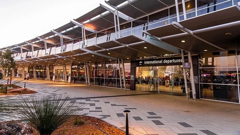 Exterior view of an airport terminal with a sign for international departures, glass facade, and modern architectural design.