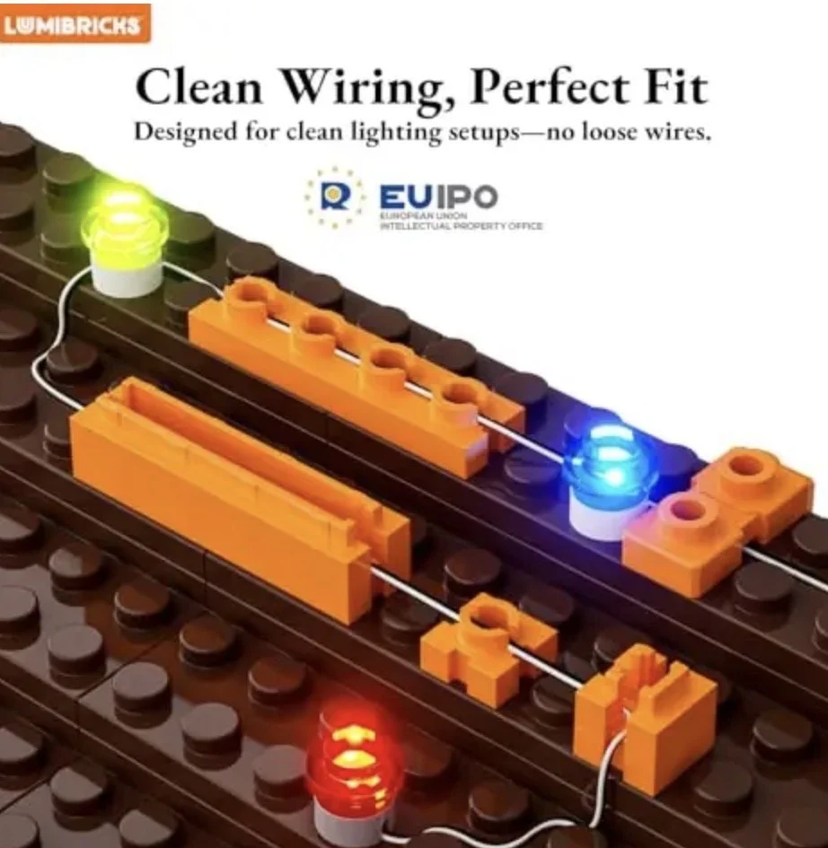 Une image montrant un ensemble de pièces LEGO orange et marron formant un panneau électrique avec des lumières LED rouges, bleues et vertes, illustrant un câblage propre pour un éclairage.