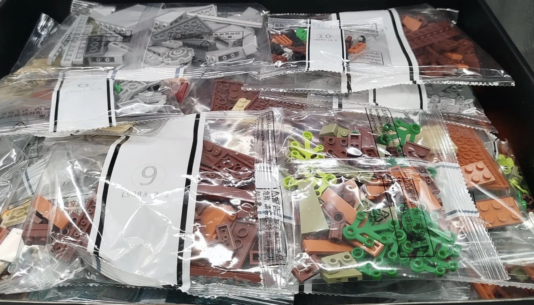 Sac de pièces LEGO en sachets translucides avec étiquettes numérotées, contenant des briques de différentes couleurs comme beige, marron, orange et vert.