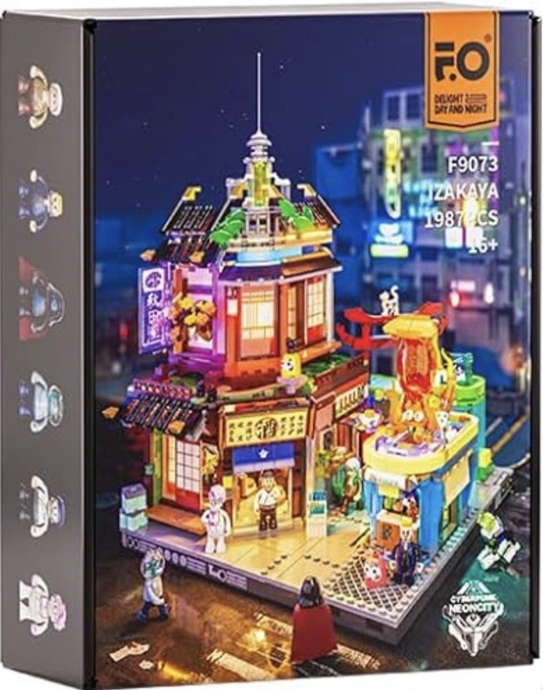 Une boîte de ensemble de construction LEGO représentant un bâtiment japonais traditionnel avec des figurines et un décor nocturne.