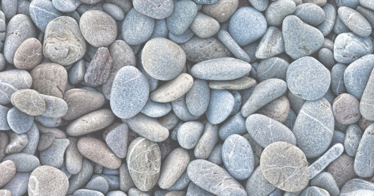 A close-up of smooth, rounded gray and light brown pebbles on a surface.