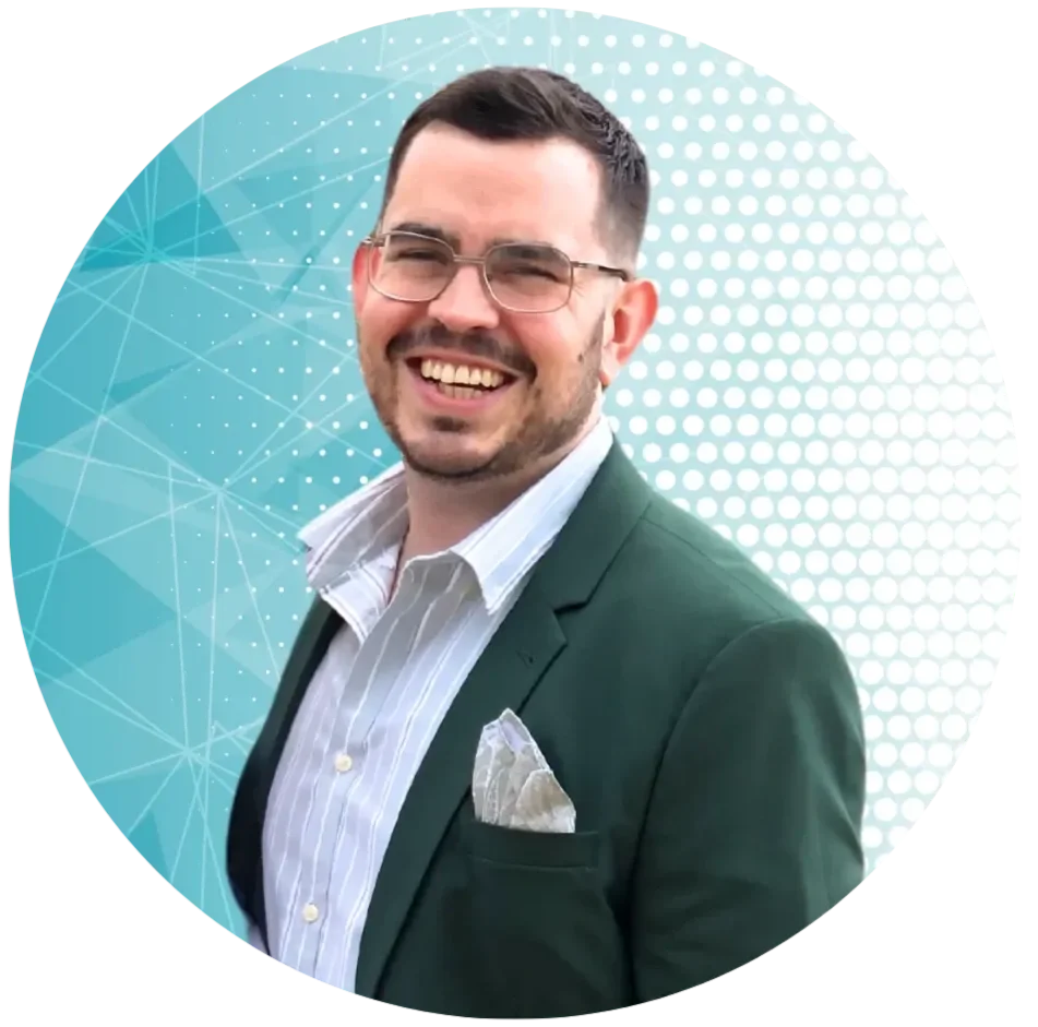 A smiling man with glasses, wearing a dark suit jacket with a white pocket square, a striped dress shirt, and standing against a digital-themed blue background.