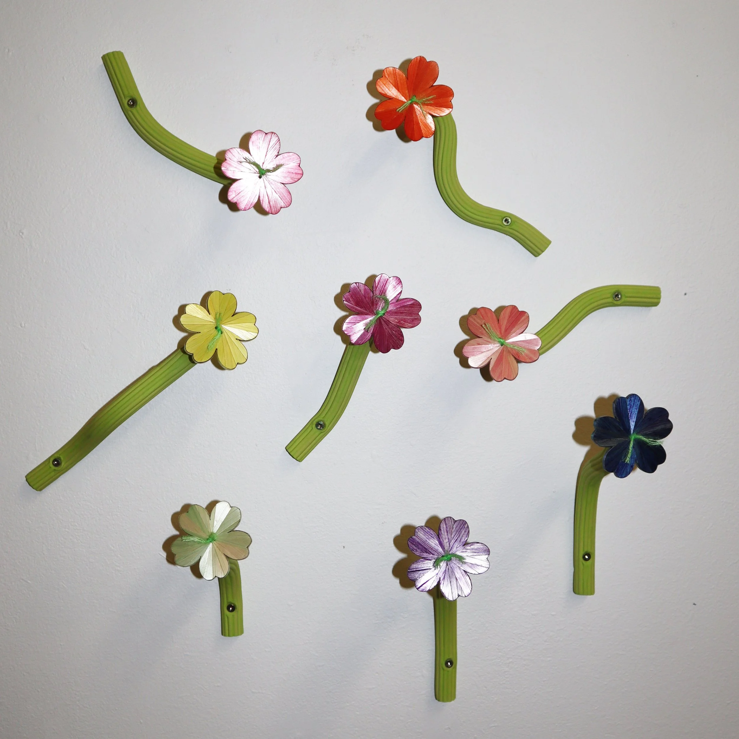 Decorative wall flowers hmade with straw and ceramics , mounted on a white wall.