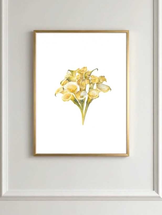 Framed art print of yellow calla lilies on a white background hanging on a wall.