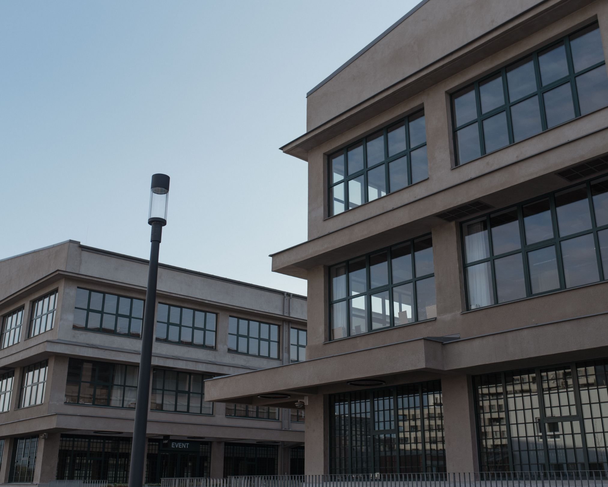 Modern multi-story building with large glass windows and a streetlamp in front.
