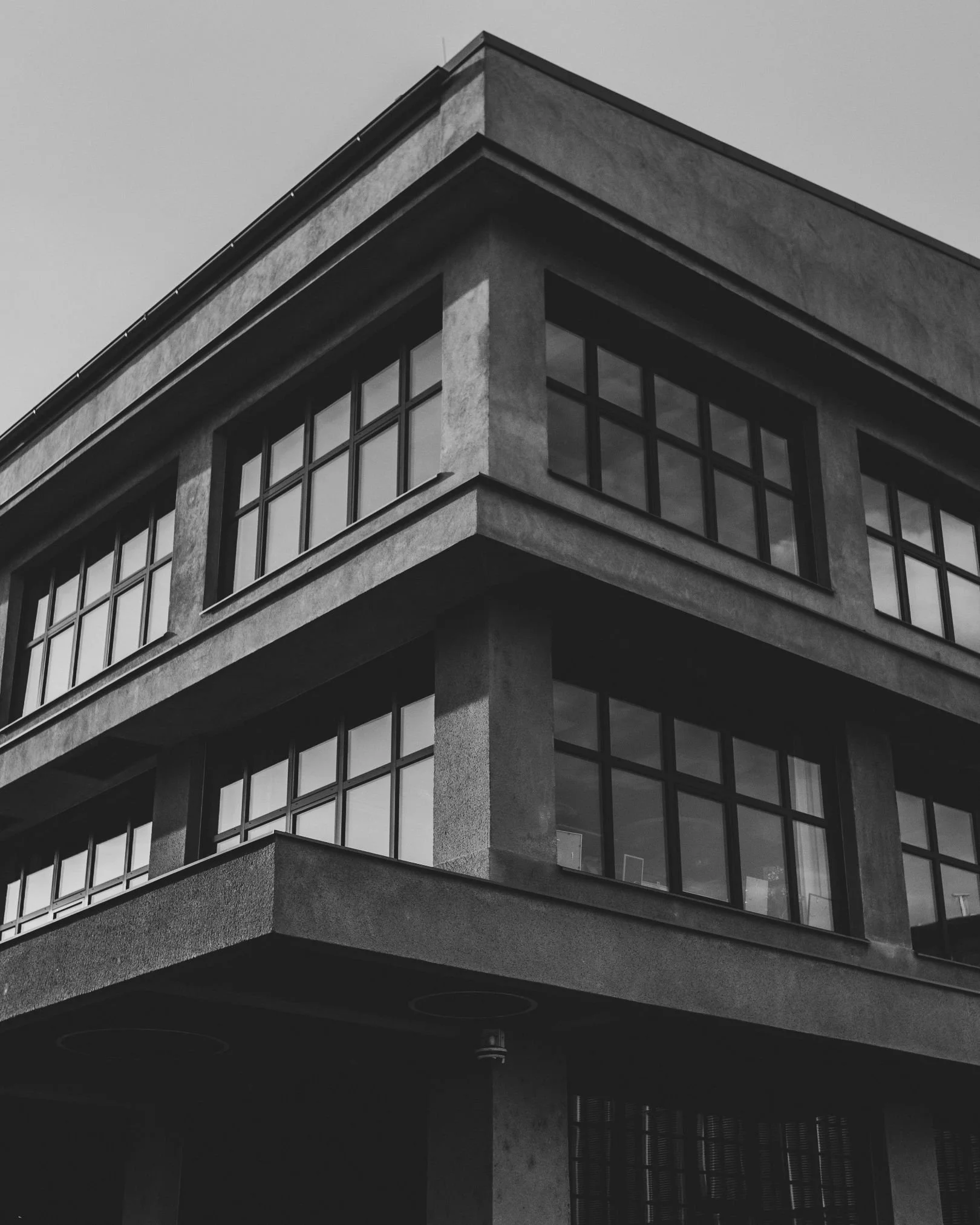 A black-and-white photo of a modern multi-story building with large square windows, showing a minimalist architectural style.