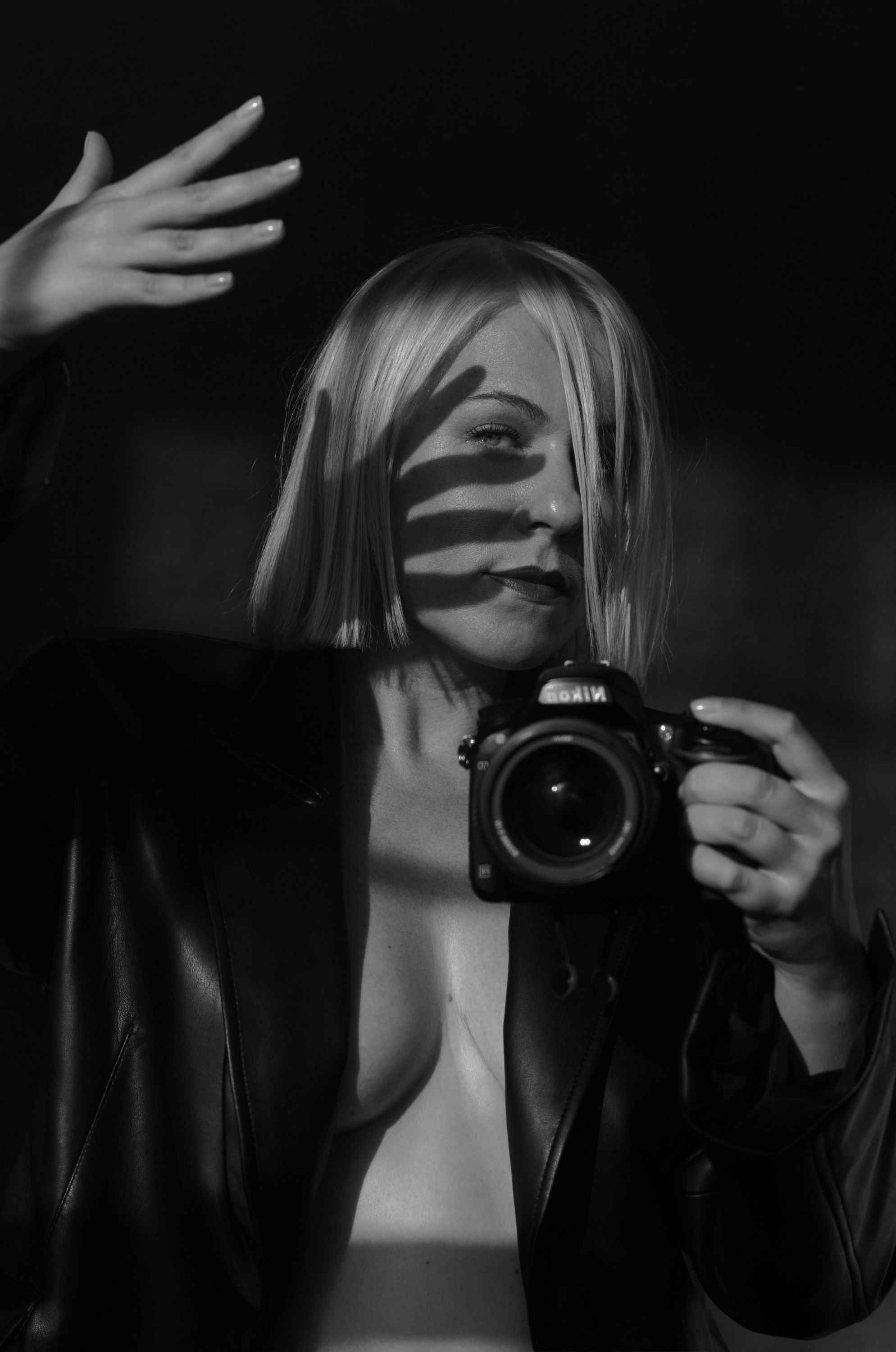 A woman takes a mirror selfie with a camera, casting shadows on her face from her hand.
