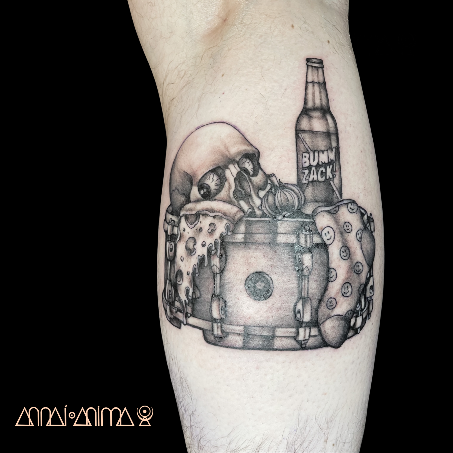 Black and gray tattoo of a skull with an eye on a tattooed arm, next to a bottle labeled "Bumm Zack!" and a cup with smiley faces, on a person's arm.
