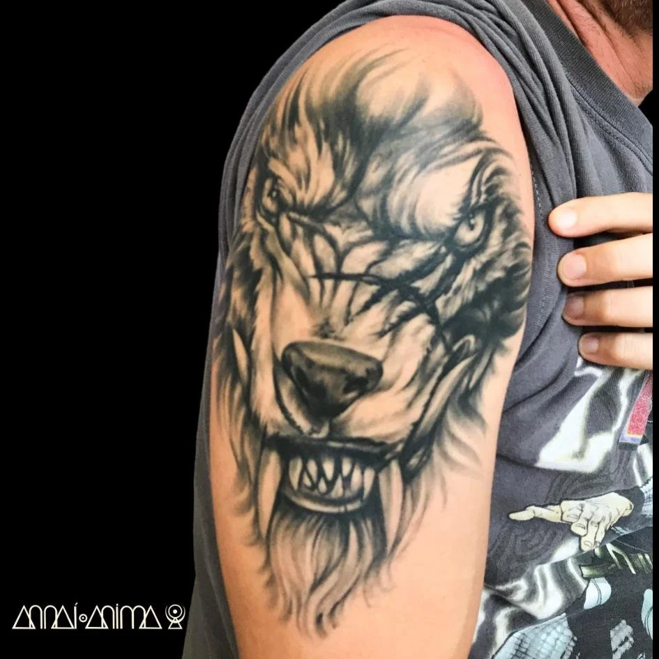 Tattoo of a roaring lion's face on a person's upper arm.
