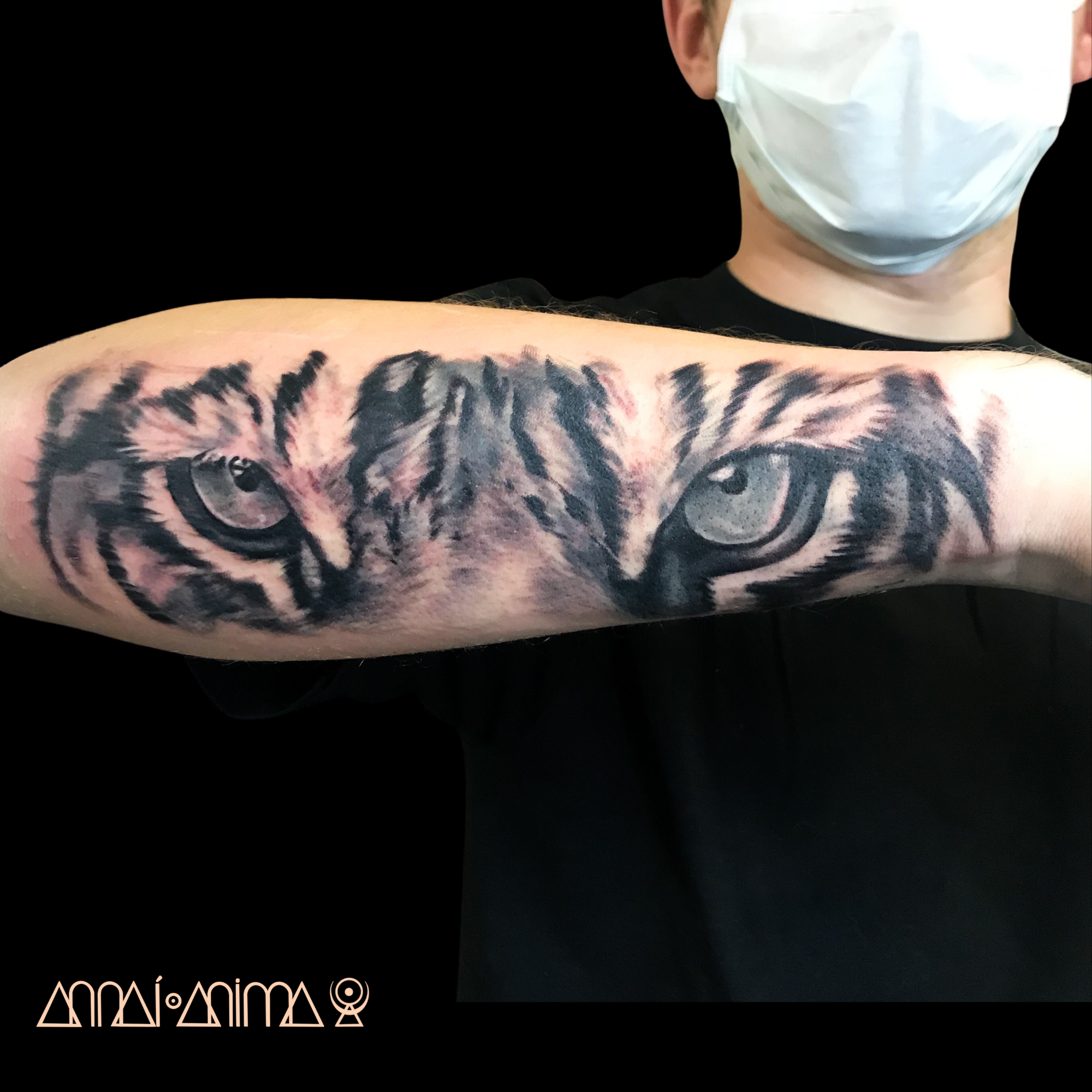 Tattoo of a tiger's face on a person's upper arm, showing detailed black and gray shading and realistic features.