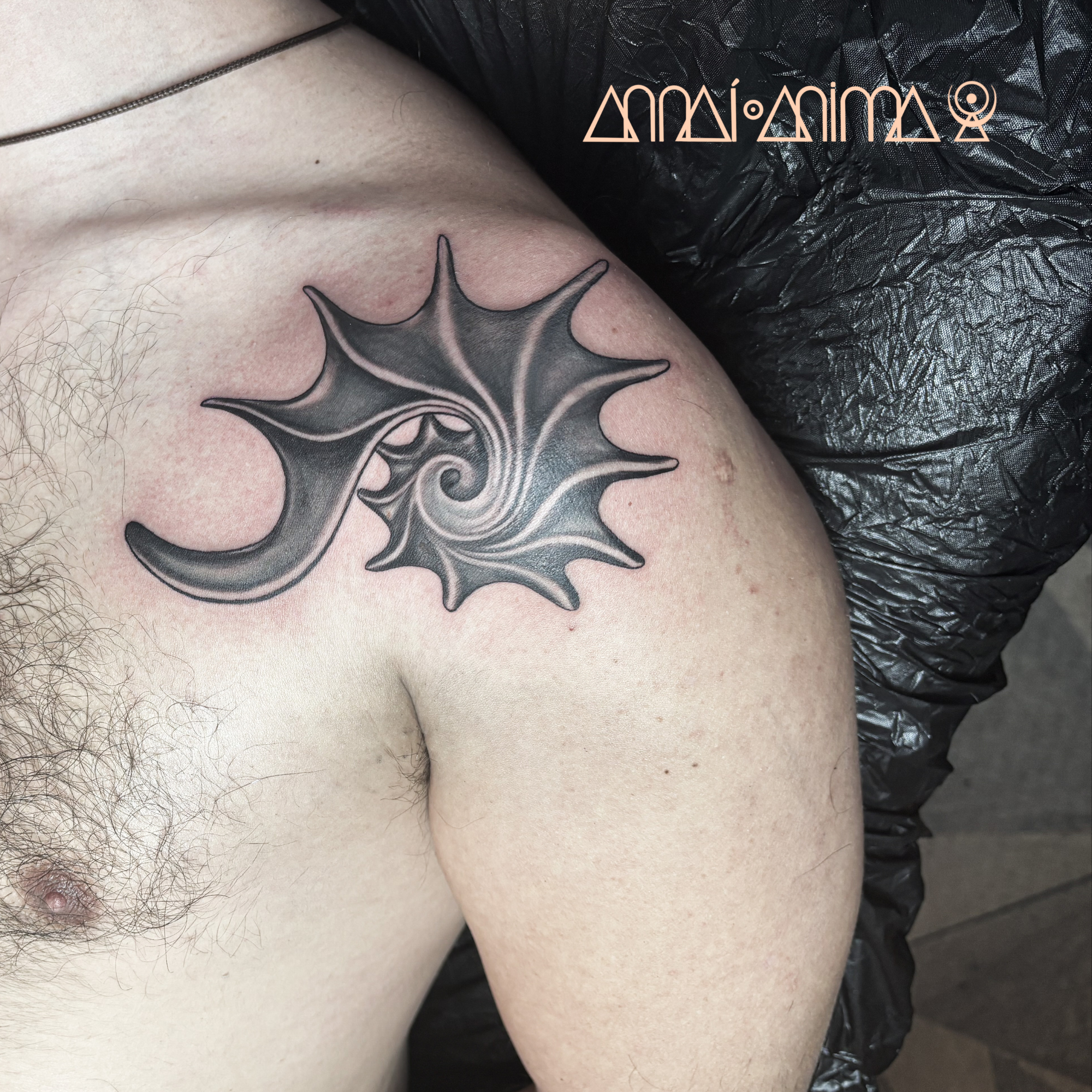 Black and grey spiral feather tattoo on upper arm and shoulder.