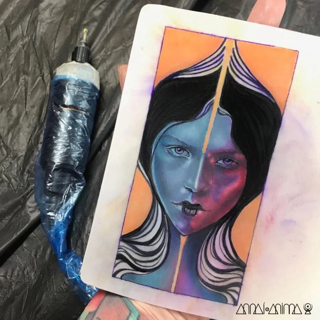 A colorful portrait of a woman with black hair, divided by a yellow line down the center of her face, with one side painted in shades of blue and the other in shades of pink and purple. The background is orange, and the portrait is on a piece of pape