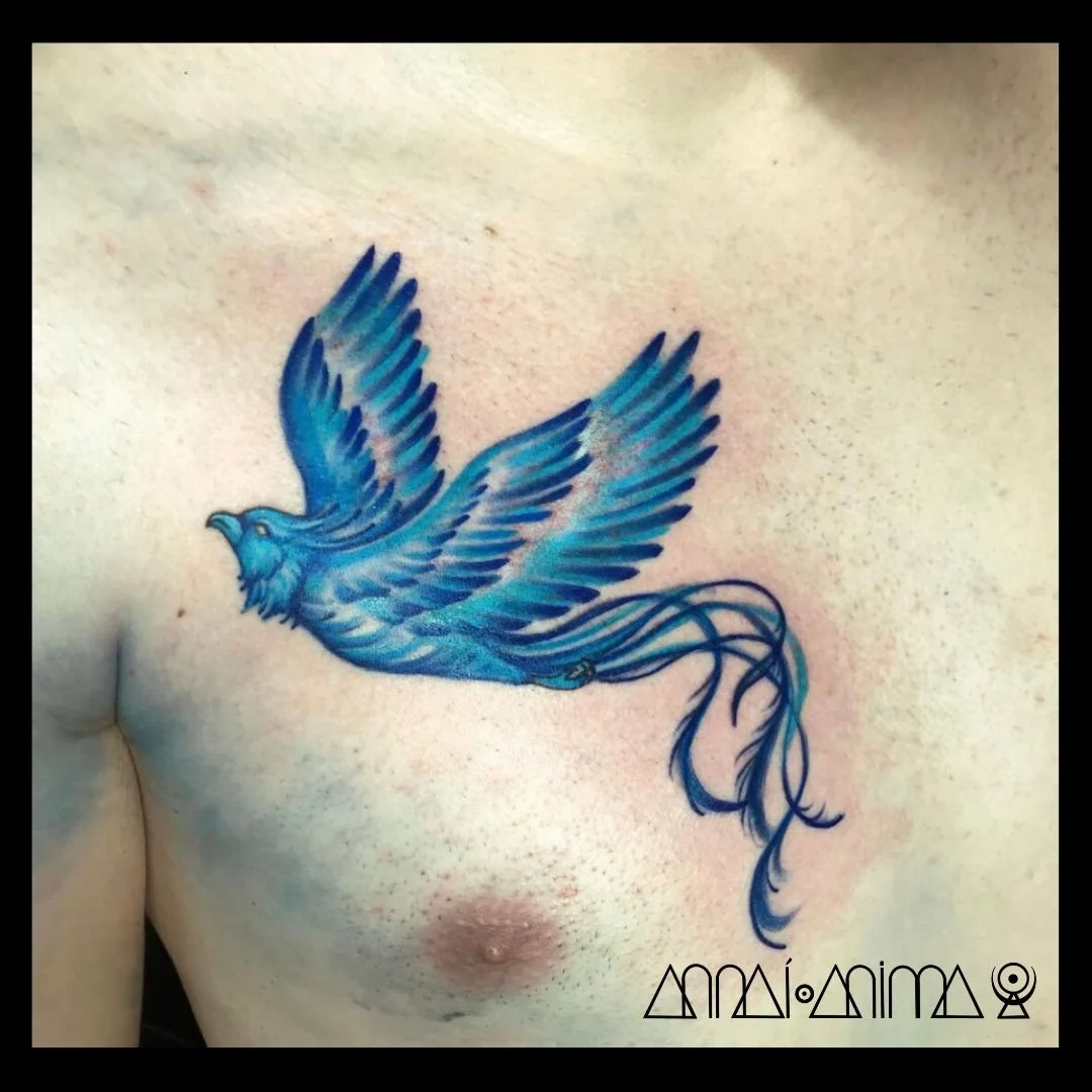 Tattoo of a blue bird in flight on a person's chest.
