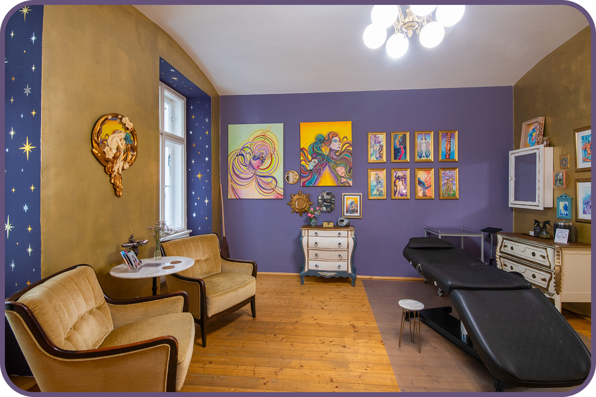Tatuarium tattoo studio in Vienna, Austria. A colorful therapy or chiropractic office with purple and gold walls, vintage furniture, framed artwork, and a medical treatment chair.