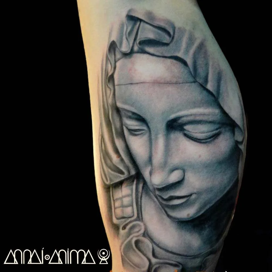 Black and gray realistic tattoo of a woman's face with her eyes closed, wearing a headscarf, on a person's upper arm.