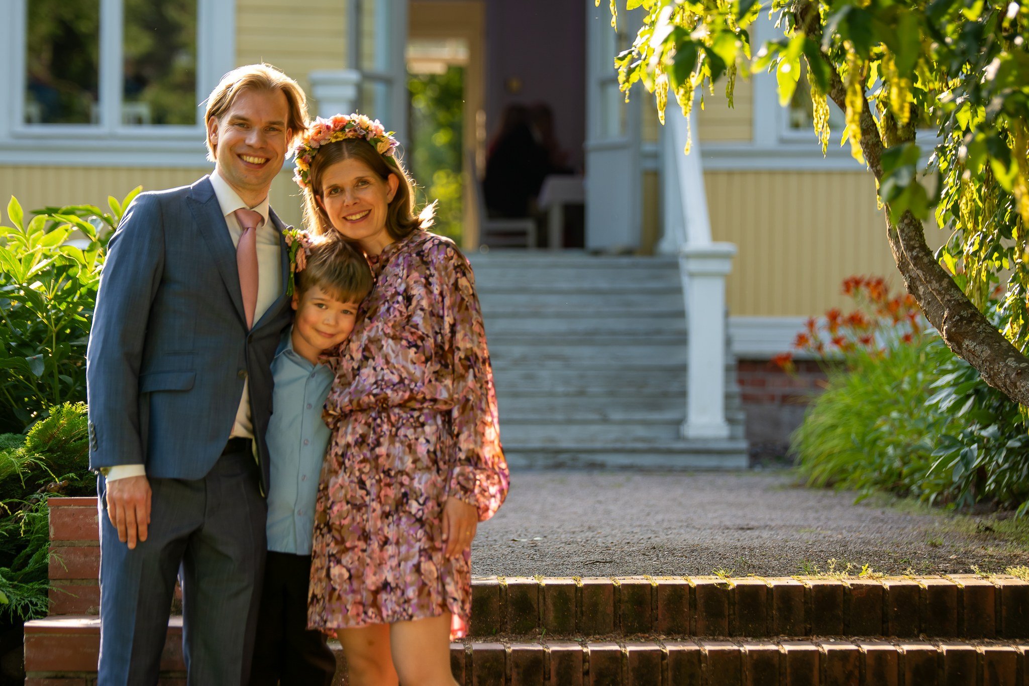 Perhe poseeraa pihalla iloisesti aurinkoisena päivänä.