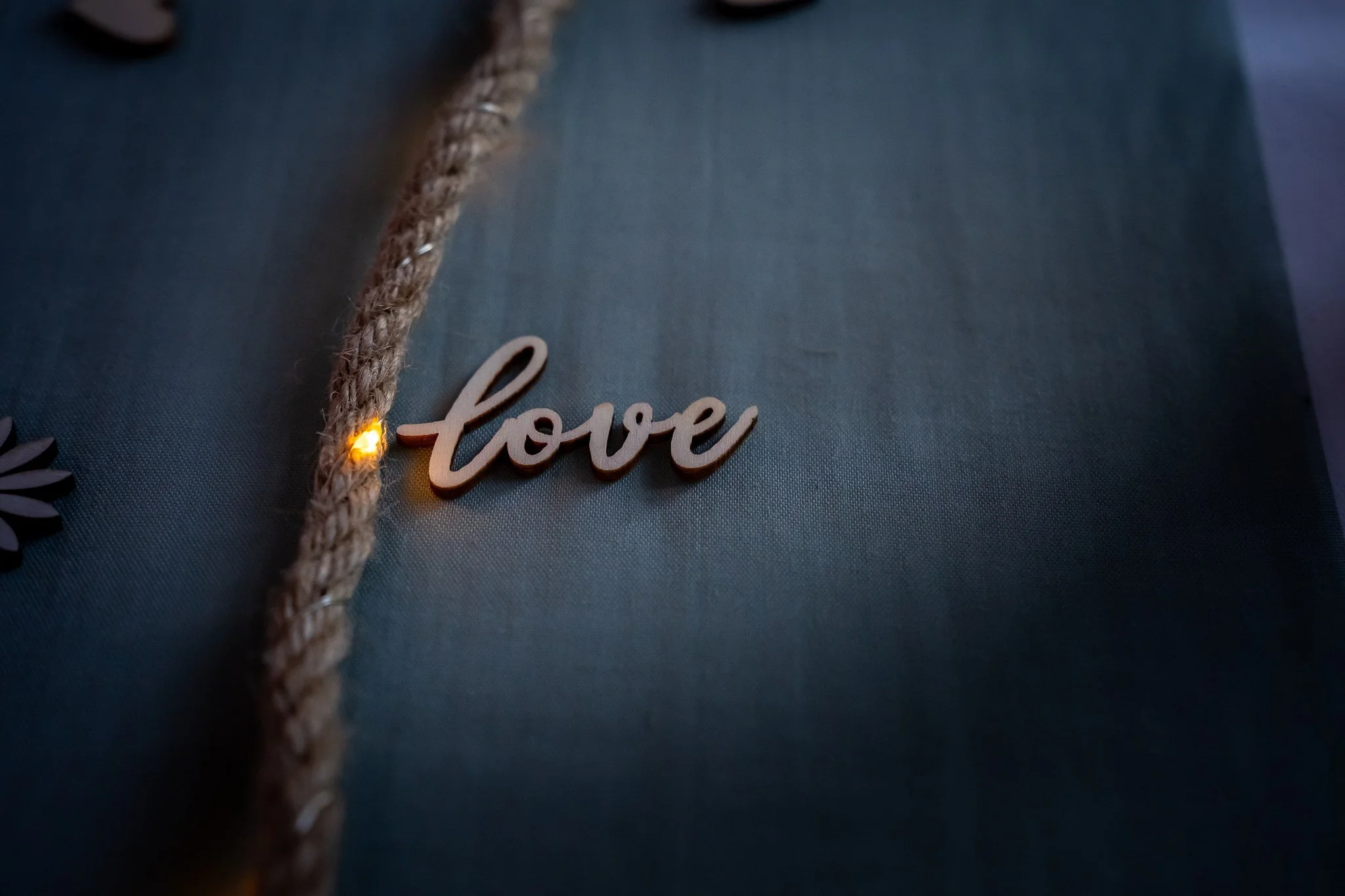 Lähikuva ehkä tie- tai reppukohteesta, jossa on puinen 'love' -merkki ja joitain pieniä valoja khaki-värisellä taustalla.