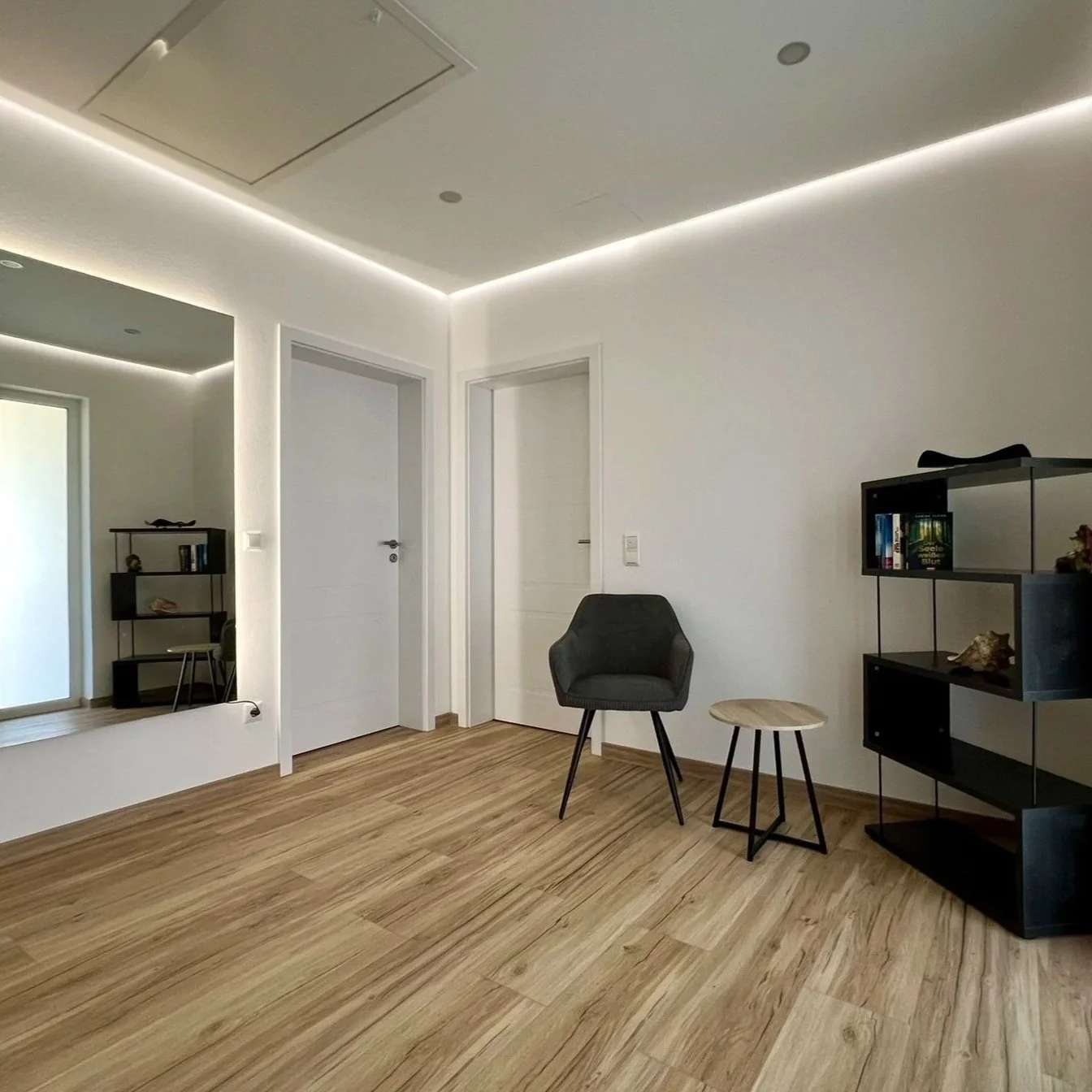 Ein modern eingerichteter Raum mit weißen Wänden und Holzfußboden, Möbeln und dekorativen Gegenständen