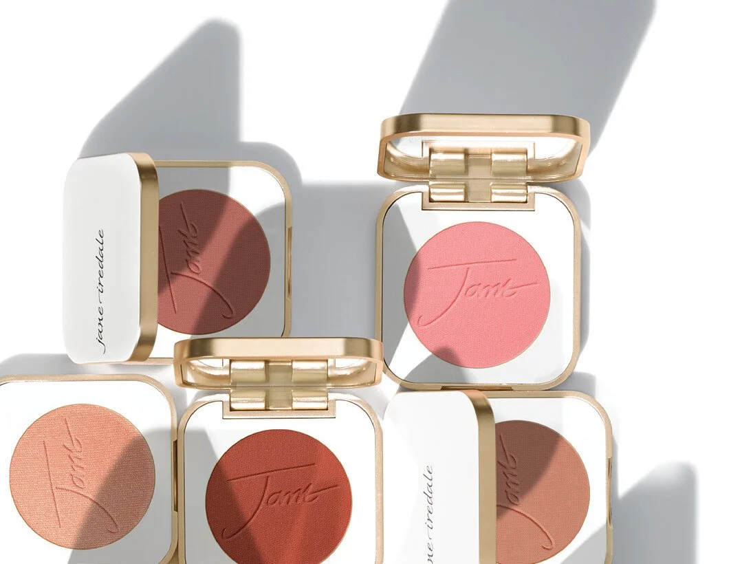 Mehrere geöffnete Jane-Iredale-Rouge-Döschen in Rosa-, Pfirsich- und Terrakottatönen