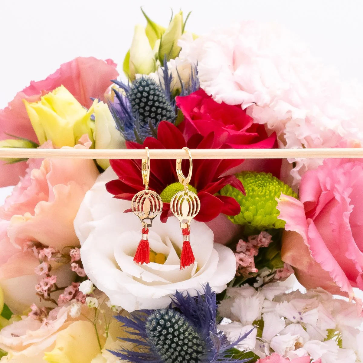 Bouquet de fleurs colorées avec des boucles d'oreilles dorées suspendues.