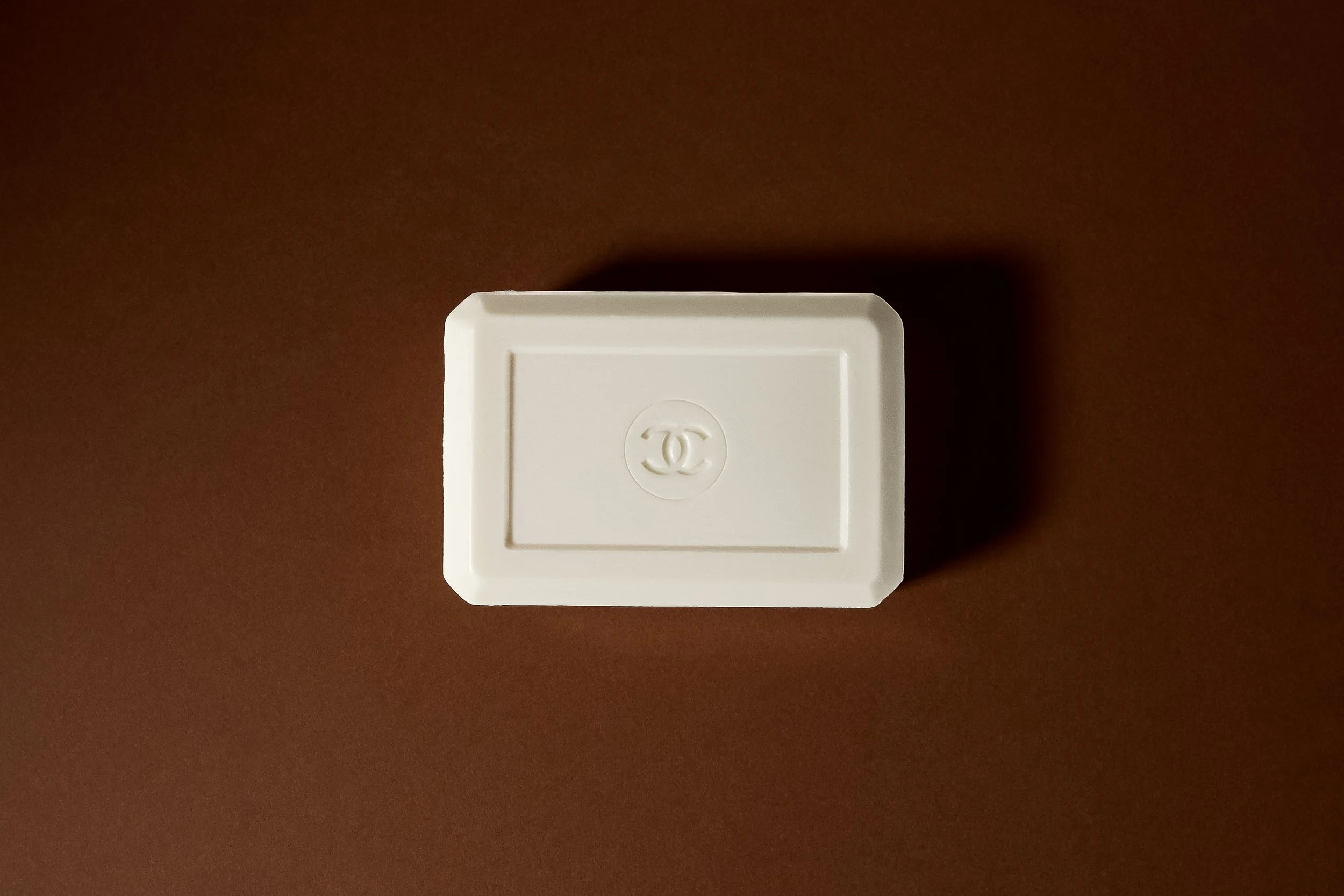 Boîte en plastique blanche avec logo Chanel embossé, vue du dessus.