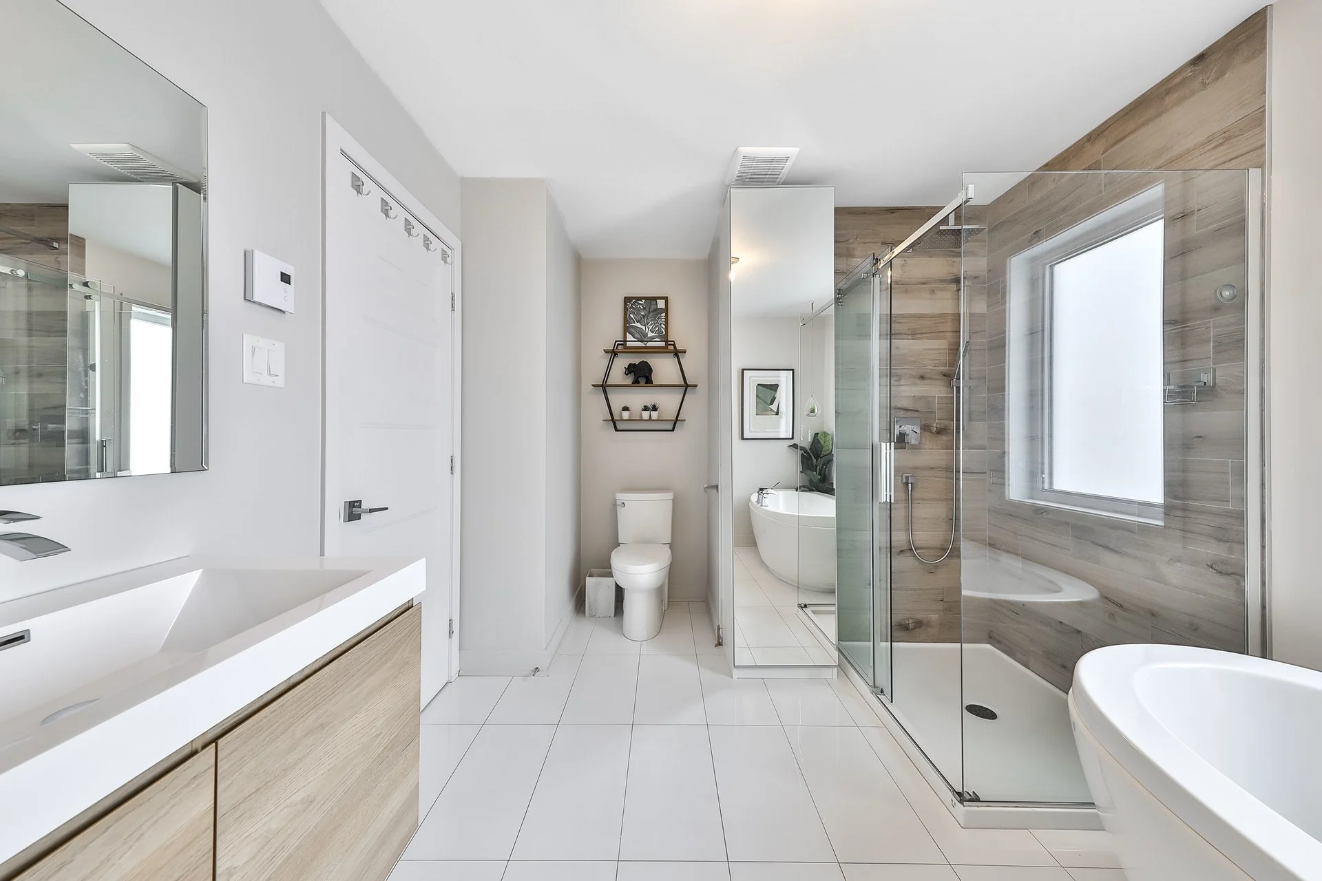 Salle de bain moderne avec douche en verre, lavabo, baignoire îlot, toilettes et décorations avec bois et plantes