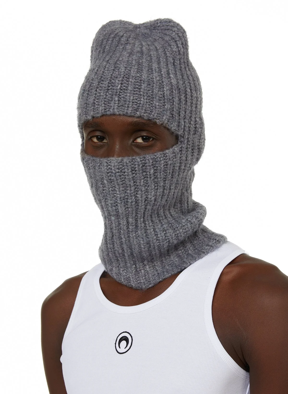 Homme portant un masque en laine gris, avec bonnet et cache-nez assortis, vêtement sans manches blanc
