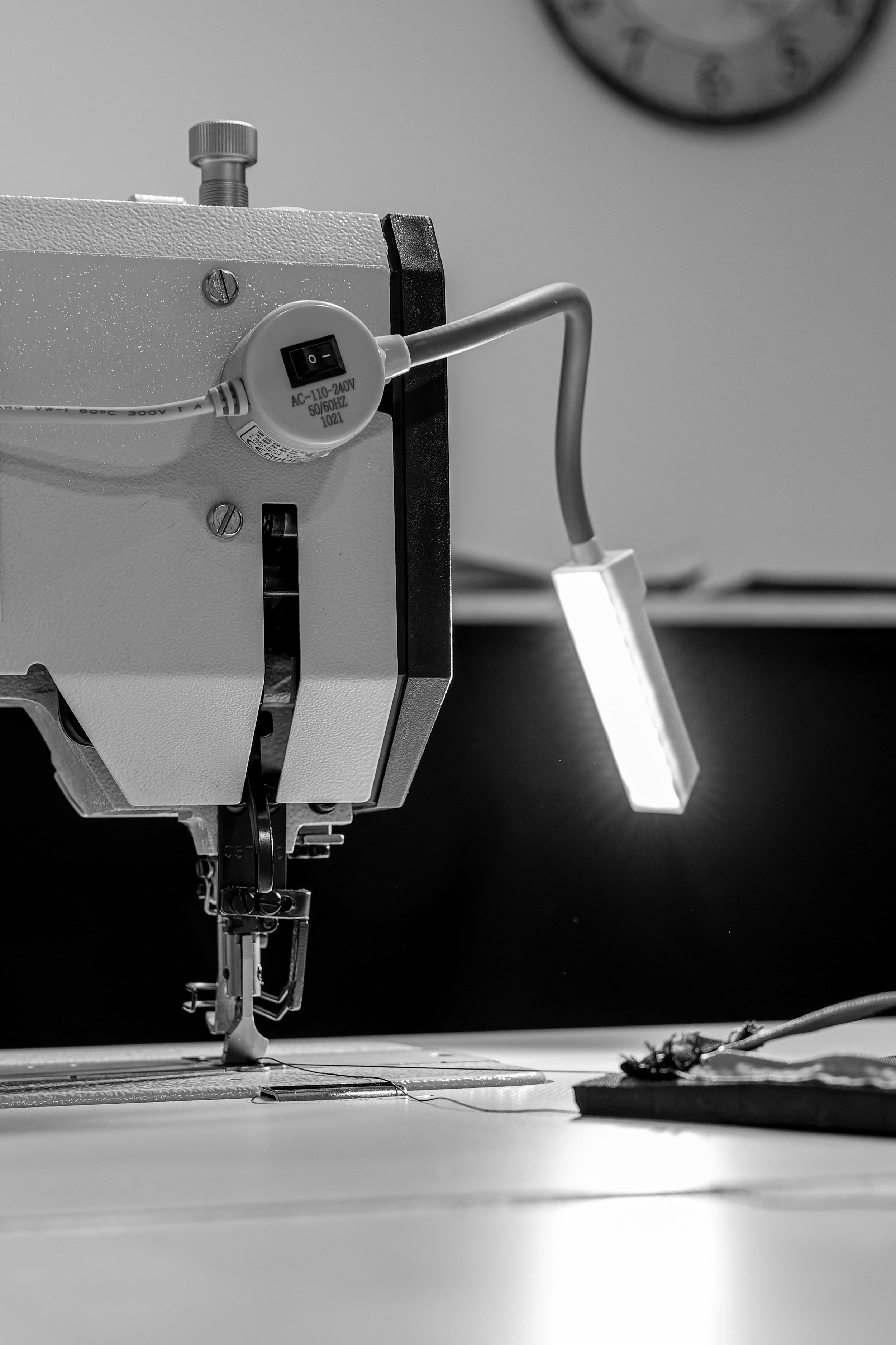 Machine à coudre industrielle avec une lumière de travail, en noir et blanc.