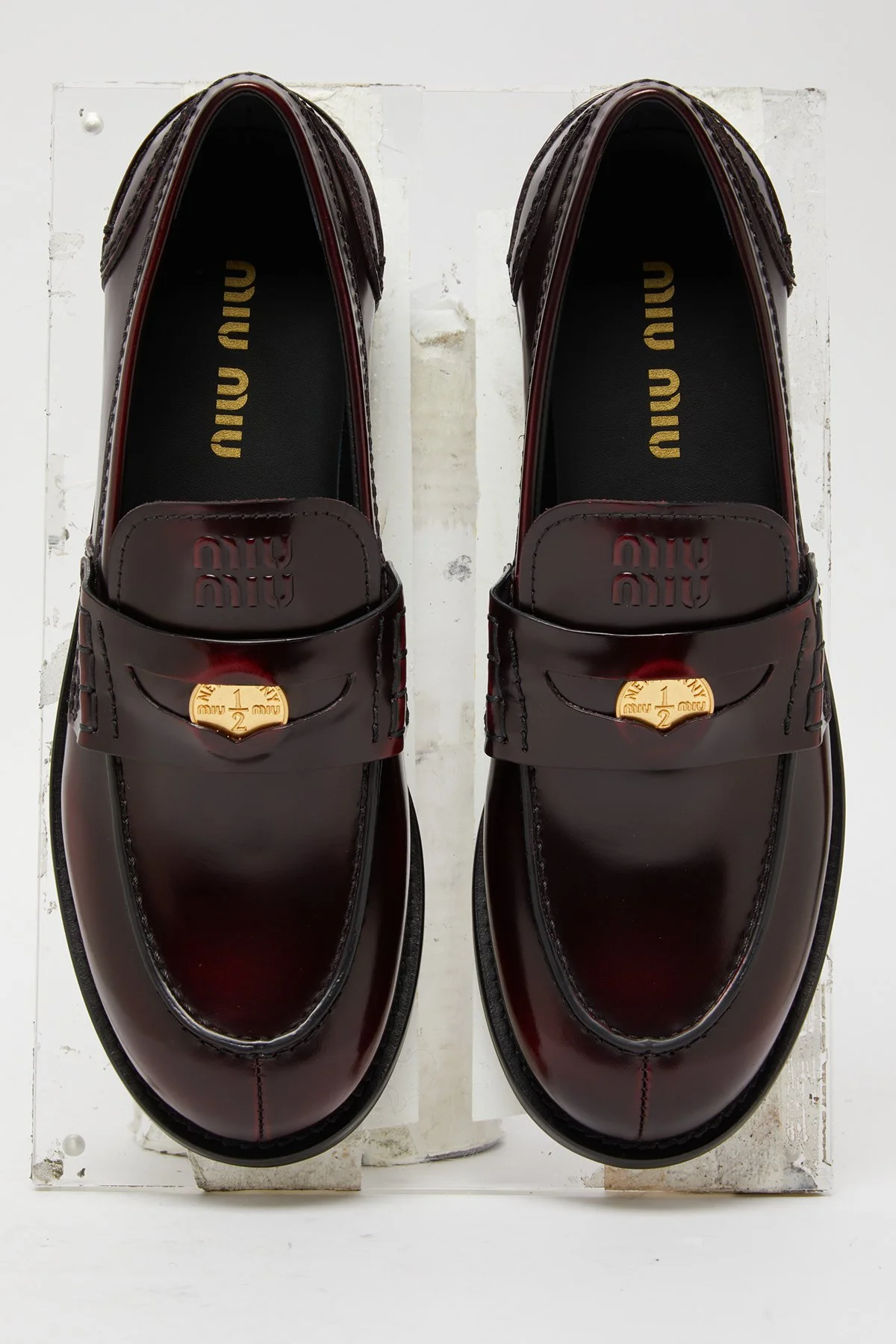 Chaussures de loafers en cuir bordeaux avec détail en or sur le dessus, vues du dessus.