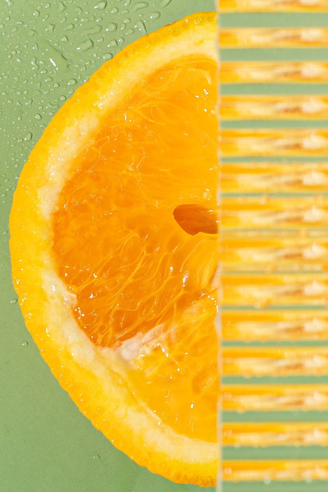 Une tranche d'orange avec une moitié de paille en plastique jaune et un fond vert.