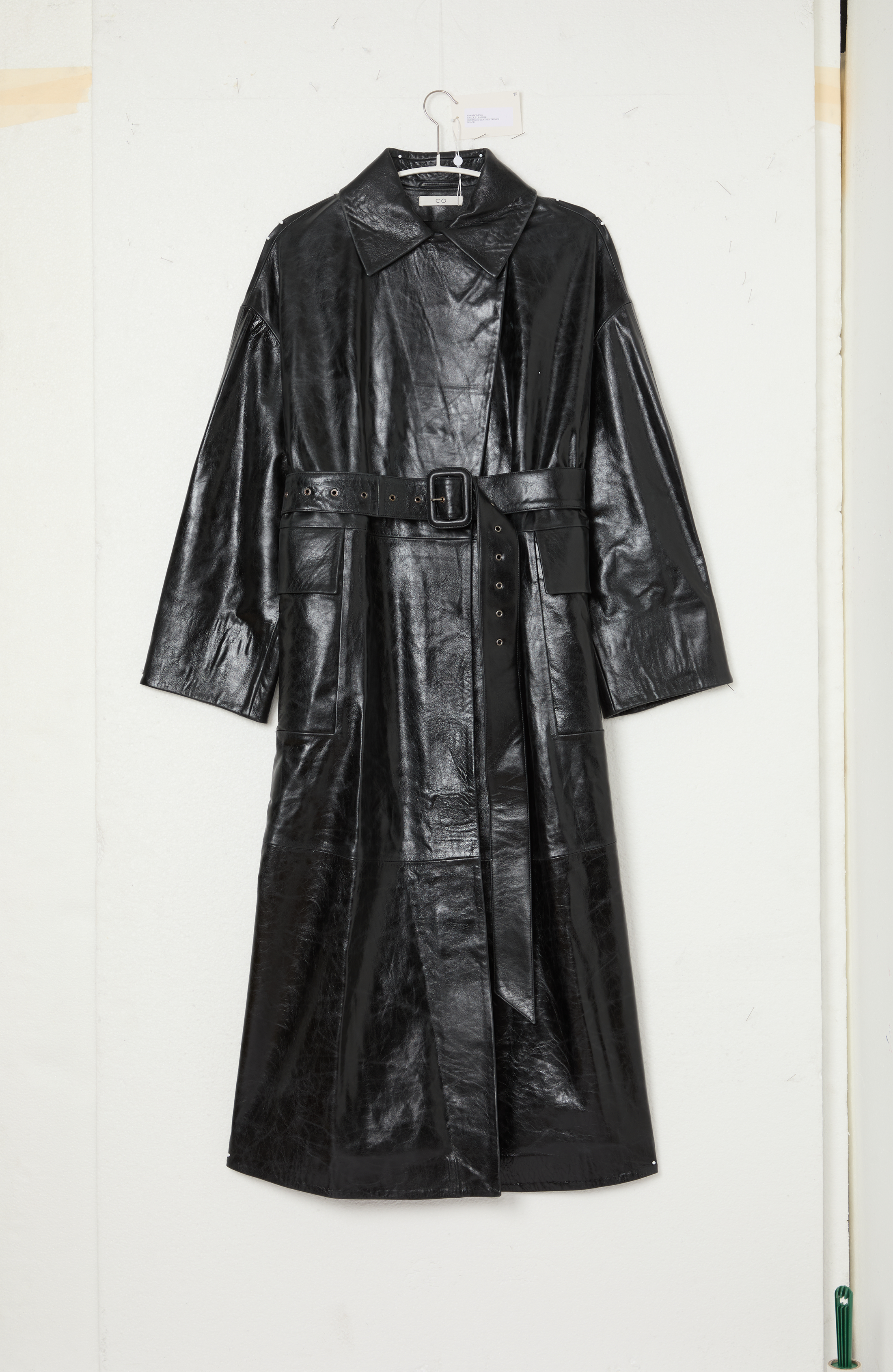Manteau long en cuir noir suspendu à un crochet.